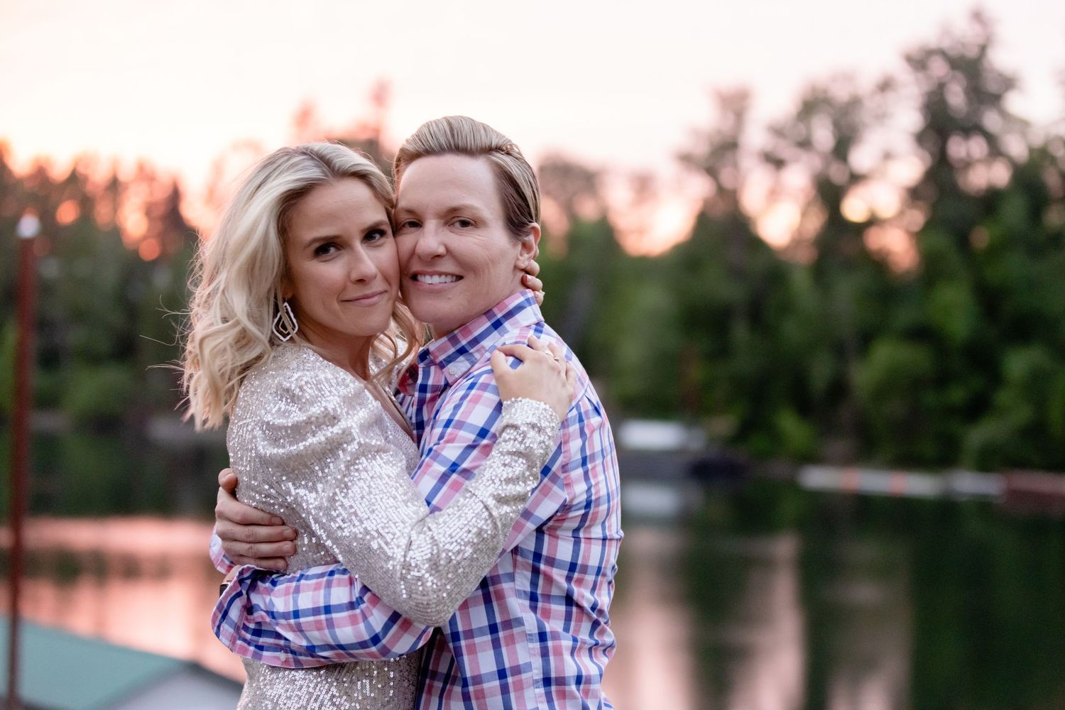 Couple embracing and smiling during sunset photoshoot by lakeside.