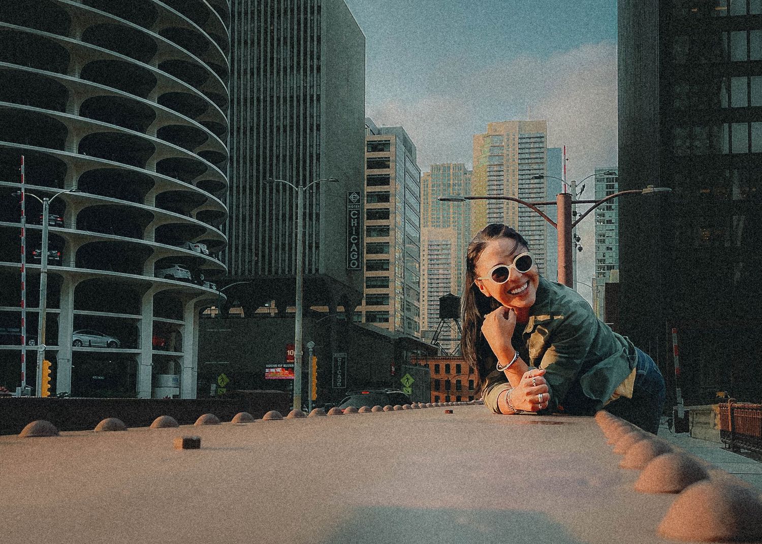 Creative urban photography showing a person lying on a city rooftop with tall buildings and Marina City towers in Chicago background.