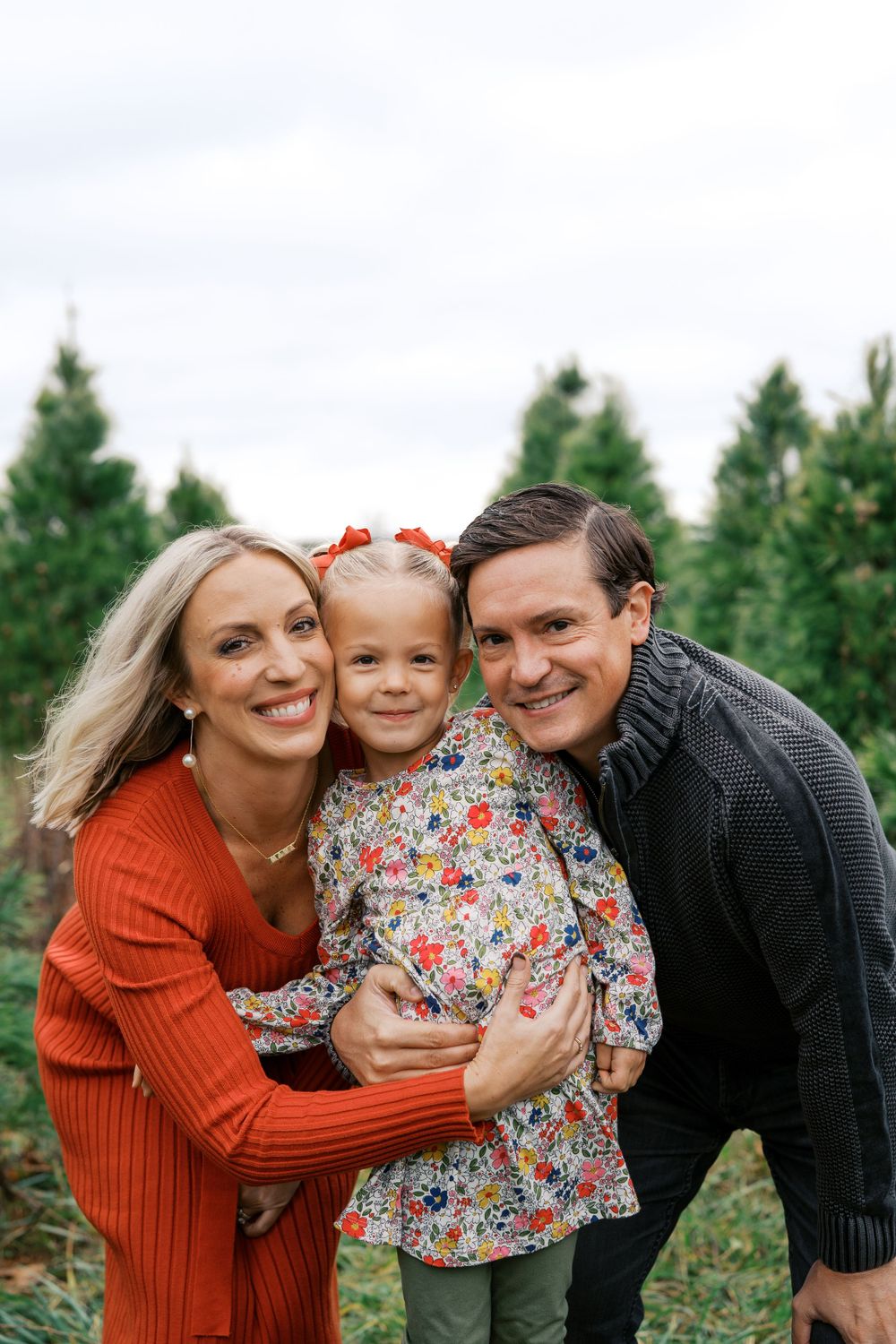 Happy family poses together at Christmas tree farm during outdoor photo session.