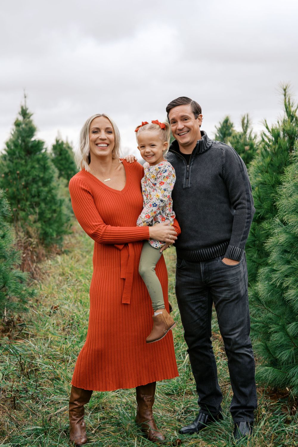 Family portrait session at a Christmas tree farm with evergreen trees in the background.