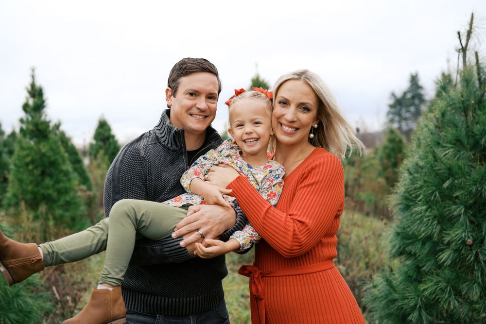Joyful outdoor family portraits taken at a Christmas tree farm during golden hour.