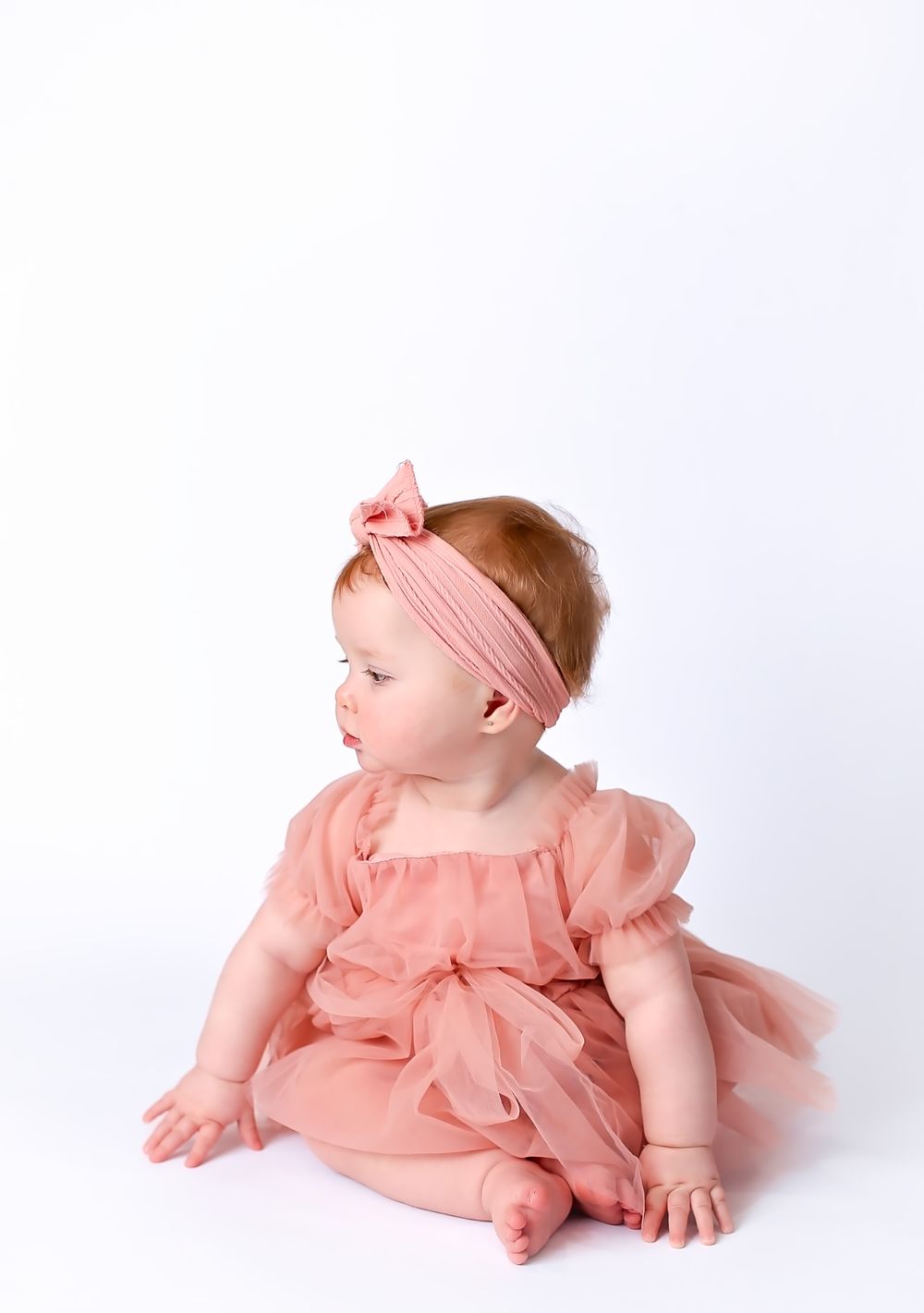 Baby girl sitting in pink dress for photos