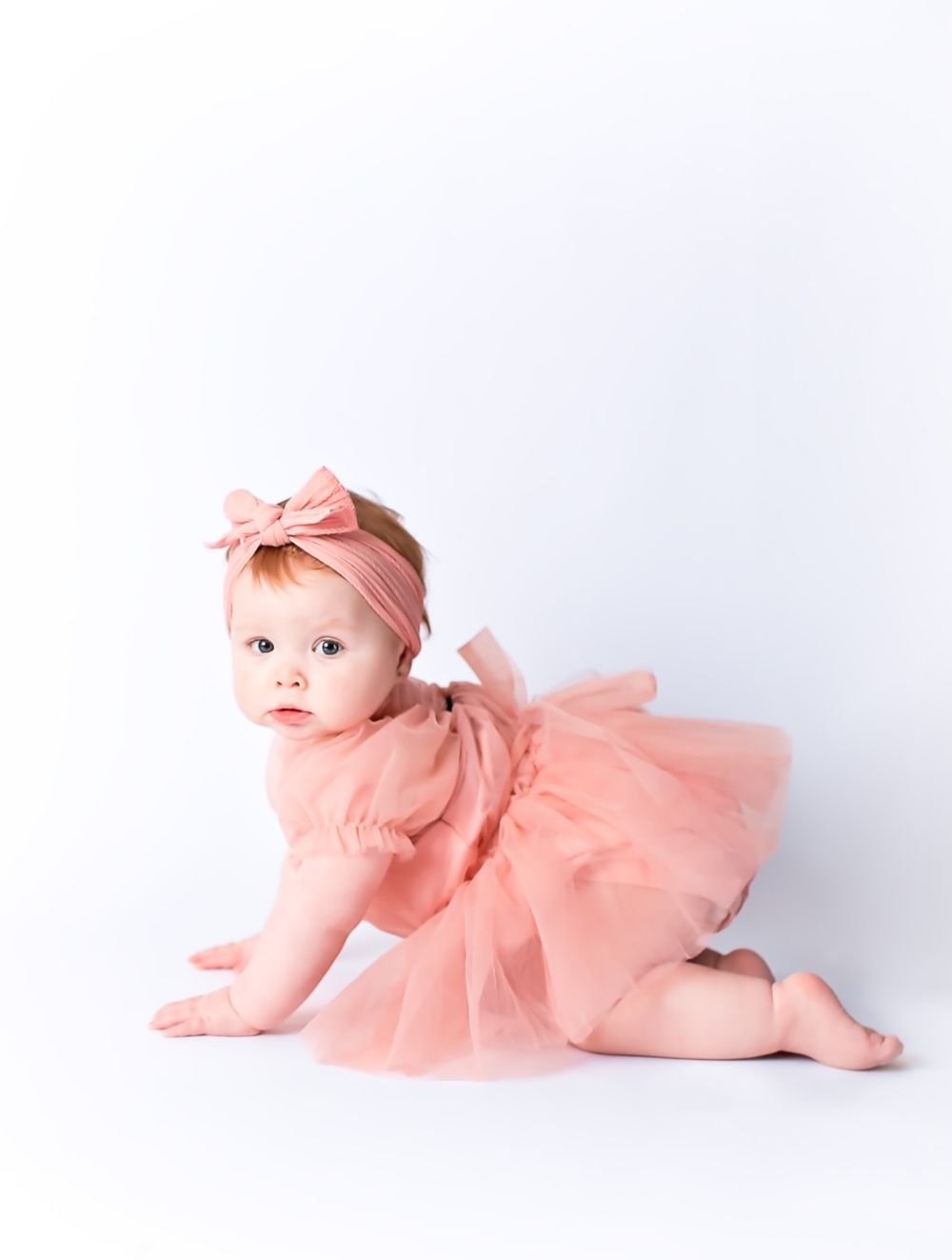 Baby girl in pink tull dress crawling