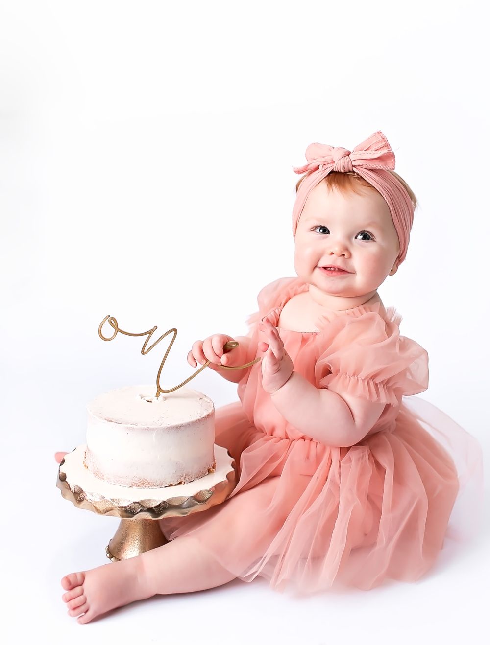 Baby girl in studio for her cake smash session eating cake
