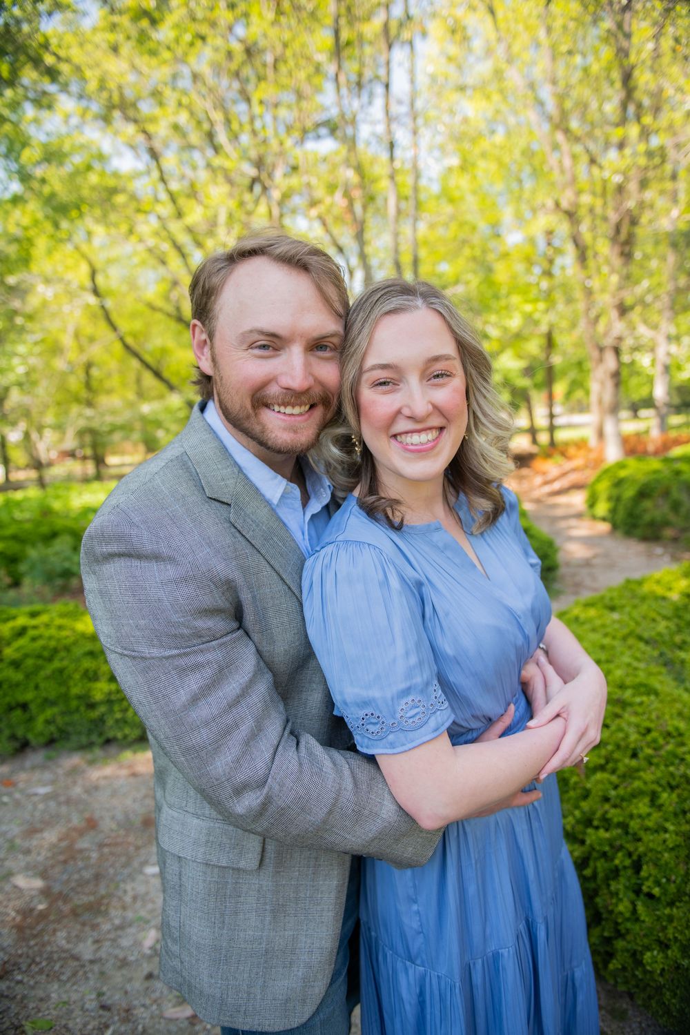 Spring engagement photos in lush garden setting with natural lighting.