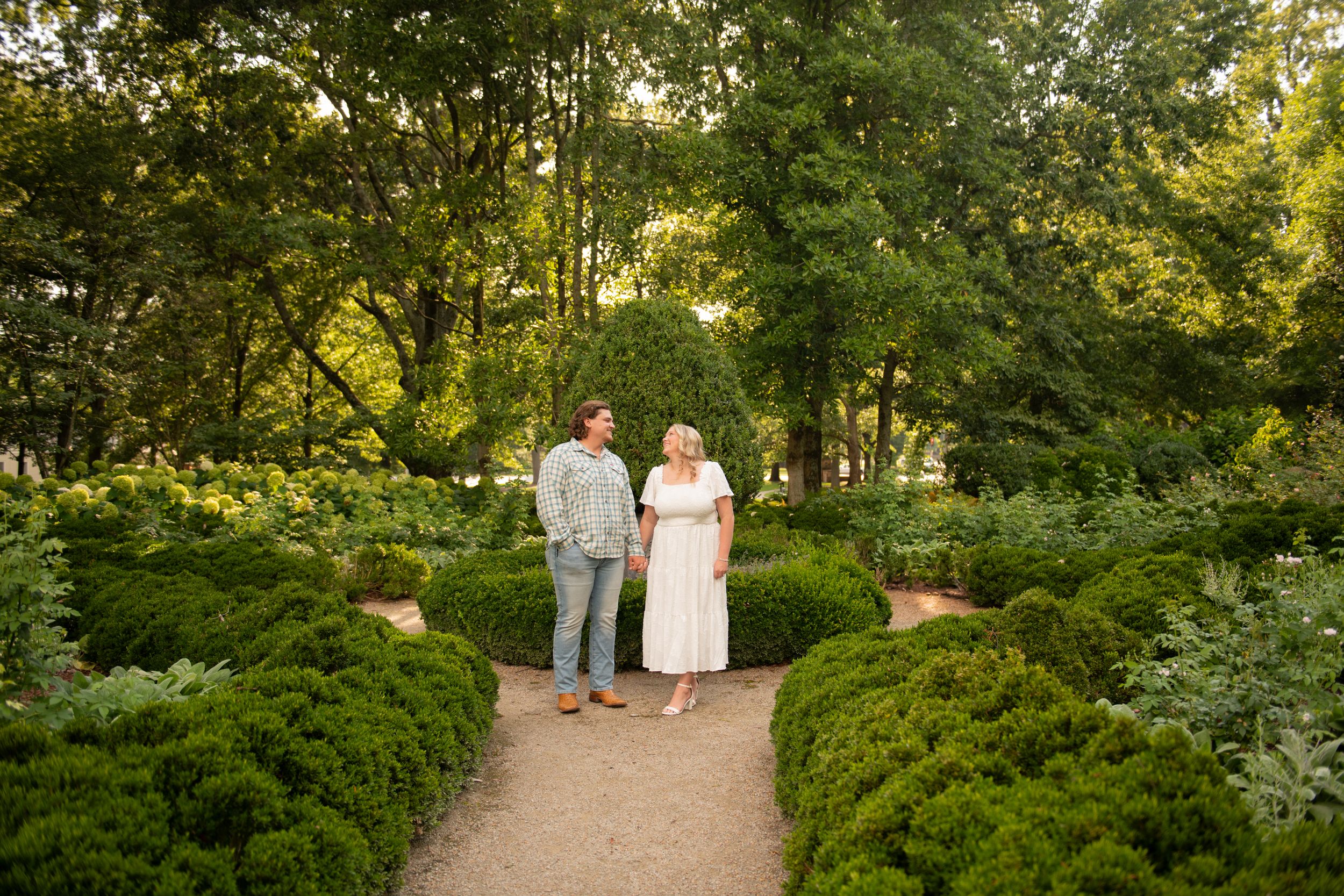Tree-lined garden pathway creates natural tunnel effect for outdoor portraits.