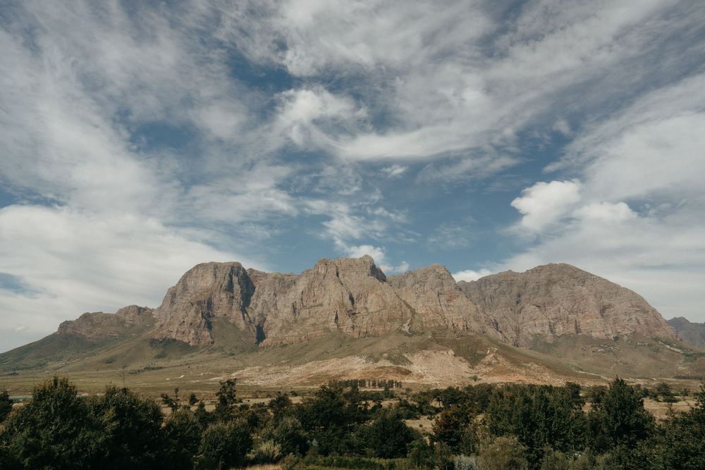 Dramatic mountain landscape with rugged peaks under cloudy blue sky.