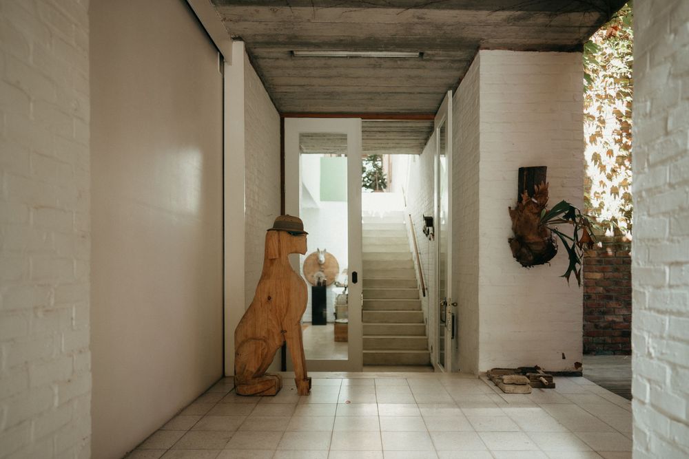 Modern hallway entrance with large dinosaur statue and white painted brick walls.