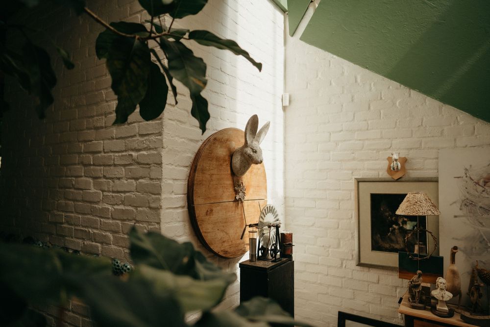 White brick wall interior with decorative clock and plant decor in moody lighting.