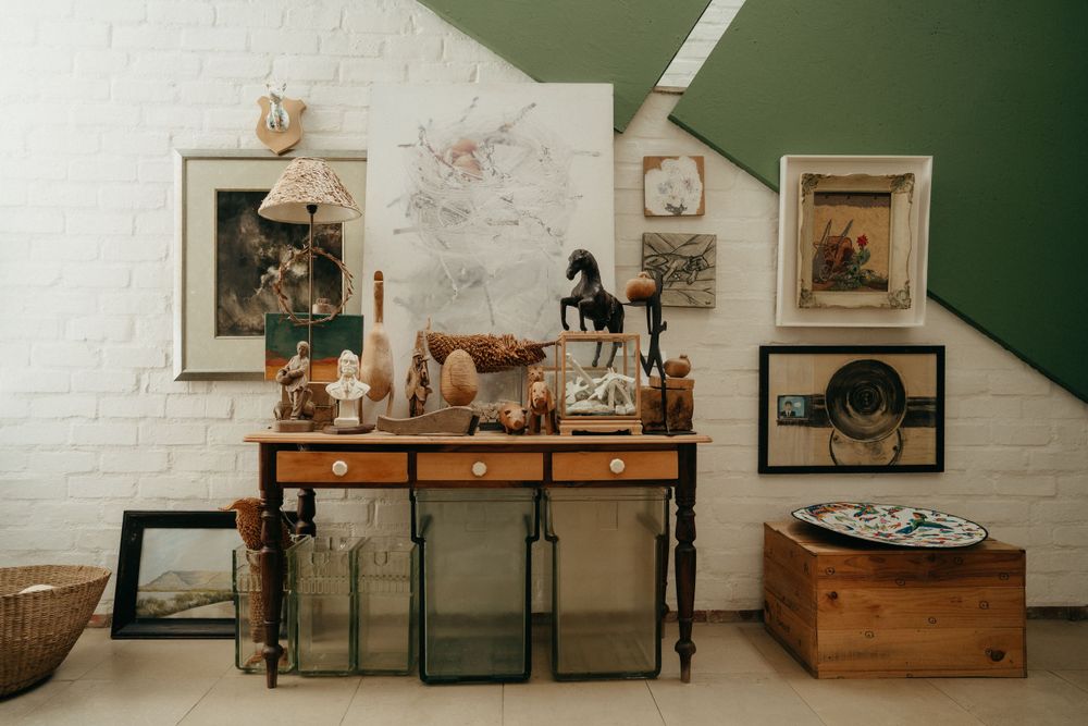A vintage-style display shelf with framed artwork and decorative objects against a white brick wall.