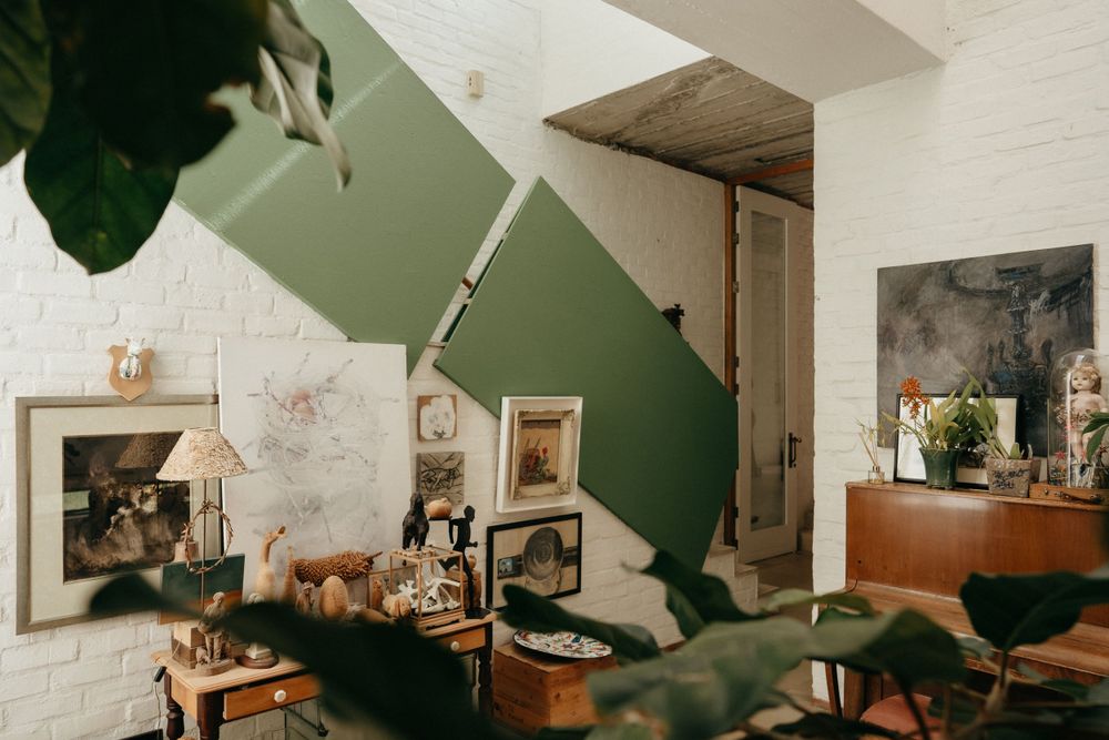 Modern living room interior with green accent wall, vintage decor and framed photos.
