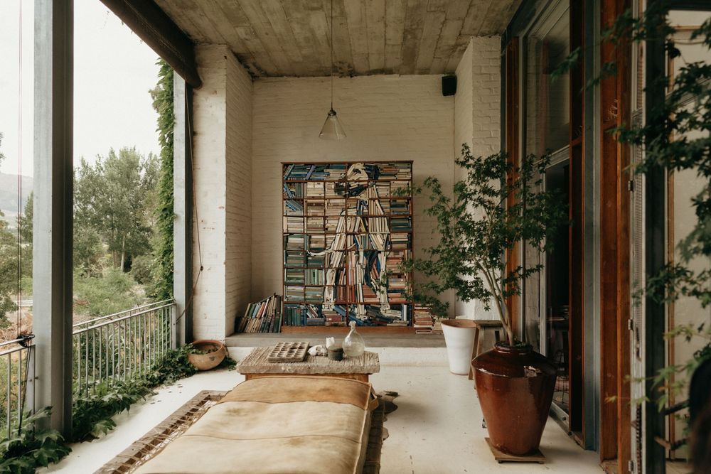 A modern concrete balcony featuring potted plants and artistic wall decorations.