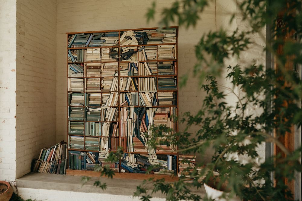Artistic wall installation made of stacked books creating dimensional artwork.