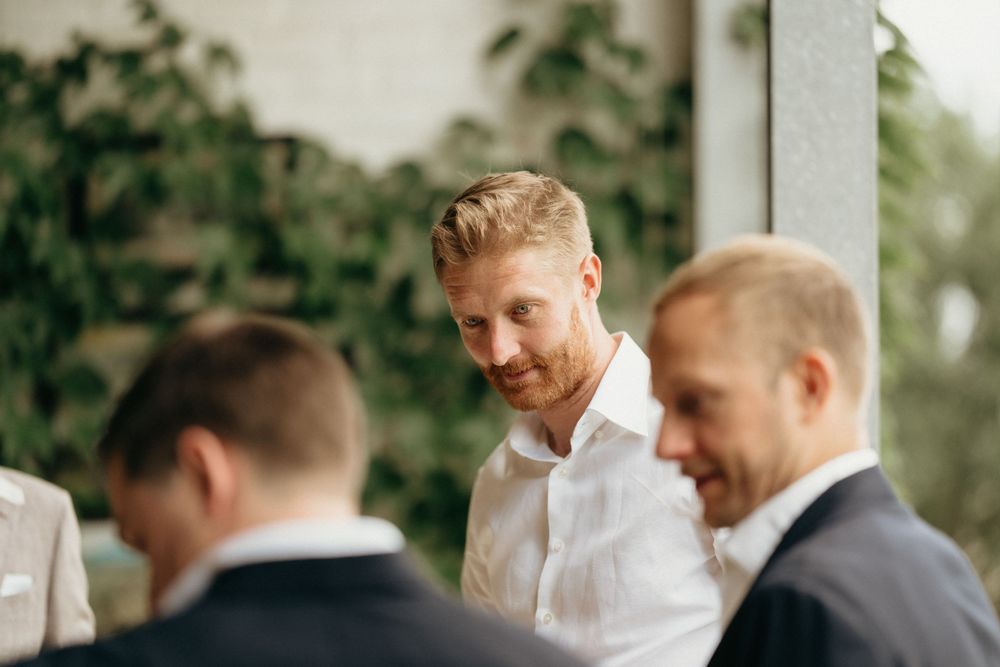 Three people sharing a light moment during a wedding celebration on a porch.