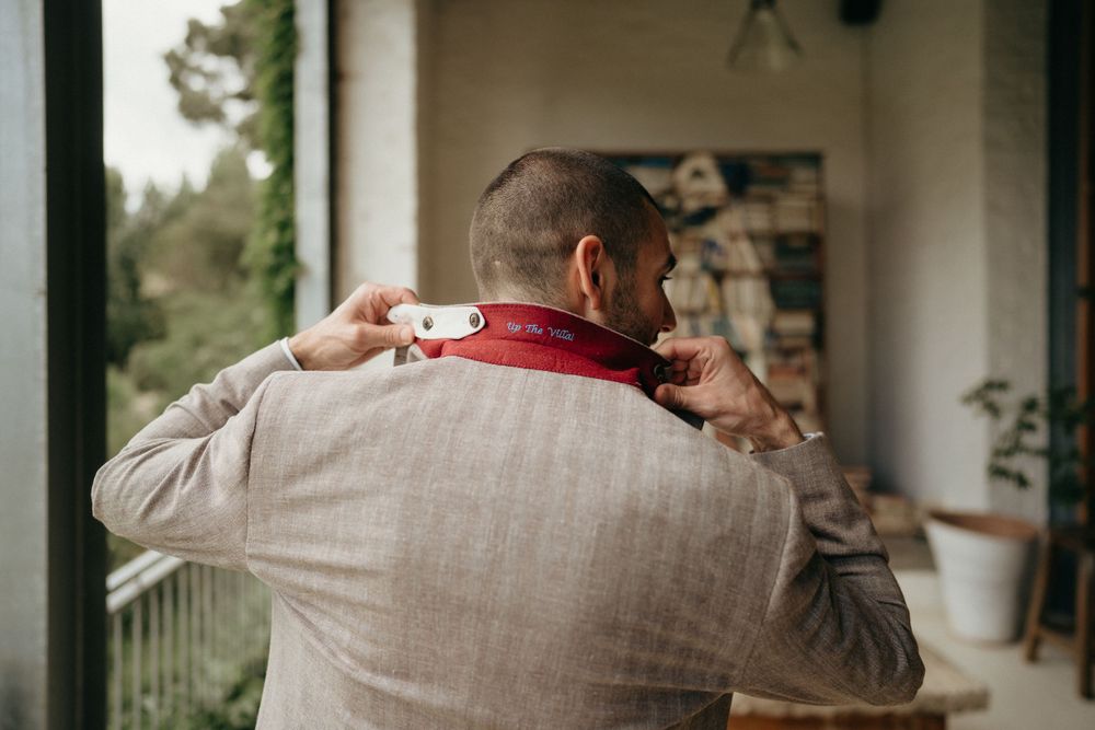 Person wearing beige jacket holds and aims camera outdoors on porch.
