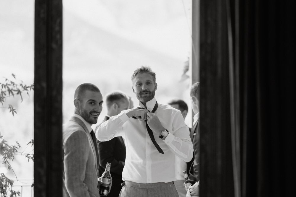 Black and white candid shot of groomsmen getting ready before the ceremony.