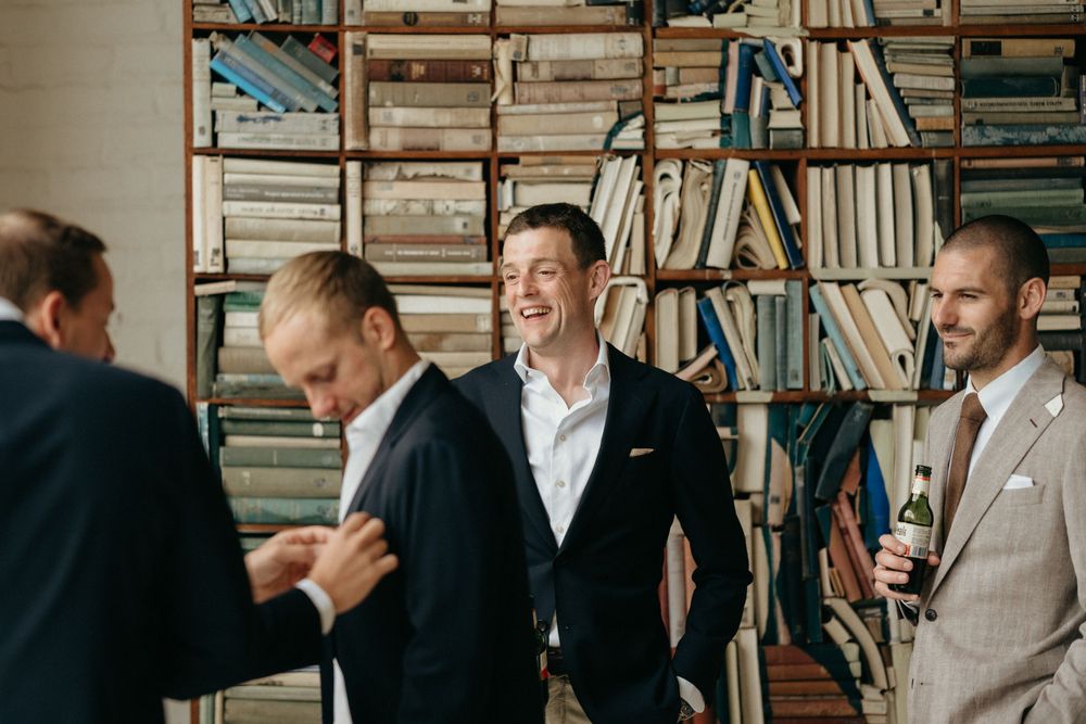 Group sharing laughs in casual formalwear against backdrop of floor-to-ceiling bookshelves.