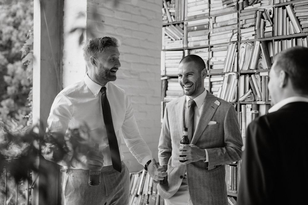 Black and white photo of wedding party members sharing conversation in casual setting.