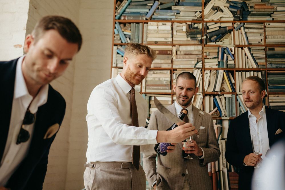 Groomsmen gather around to look at something on a device during wedding preparations.