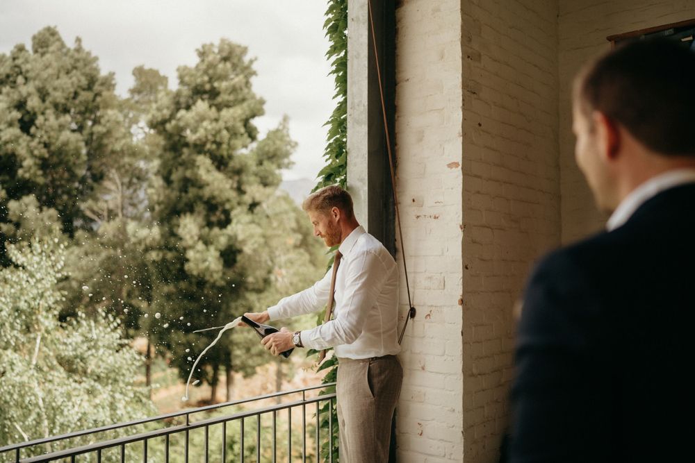 Wedding day preparation moment on a balcony with greenery in background.
