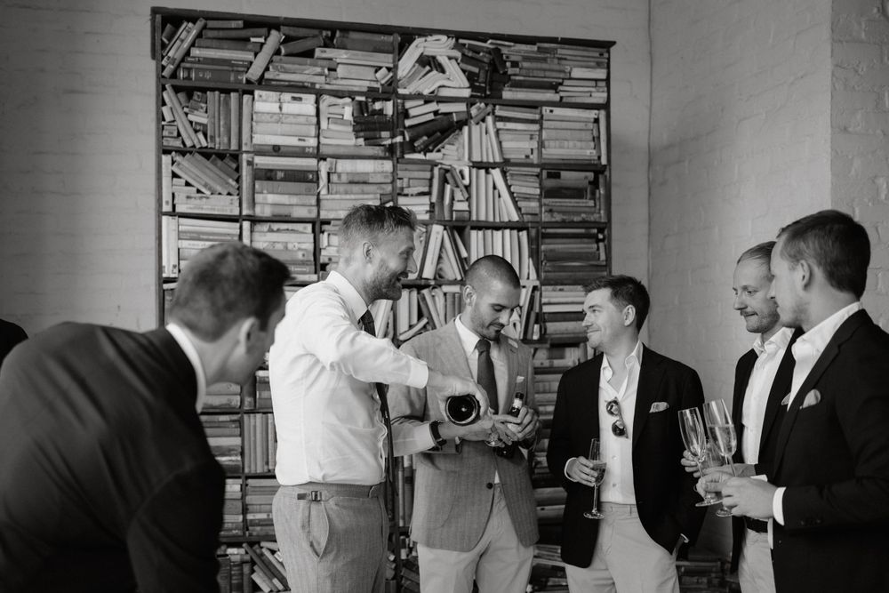 Black and white photo of groomsmen socializing before wedding ceremony.