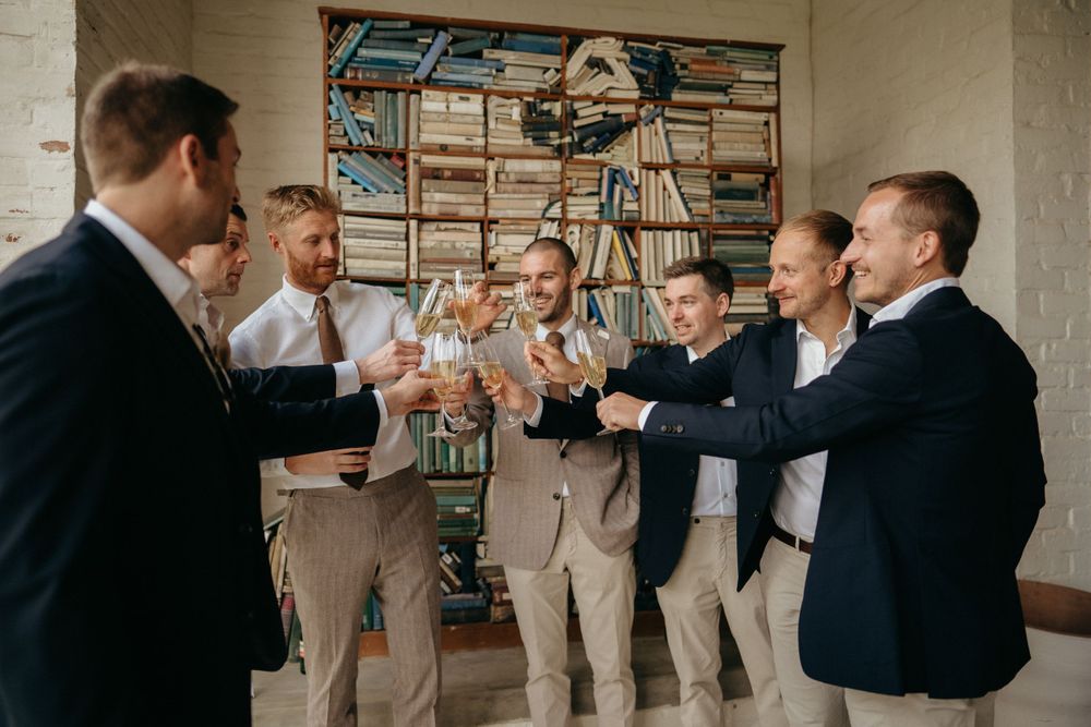 Groomsmen toasting with drinks in casual celebration.