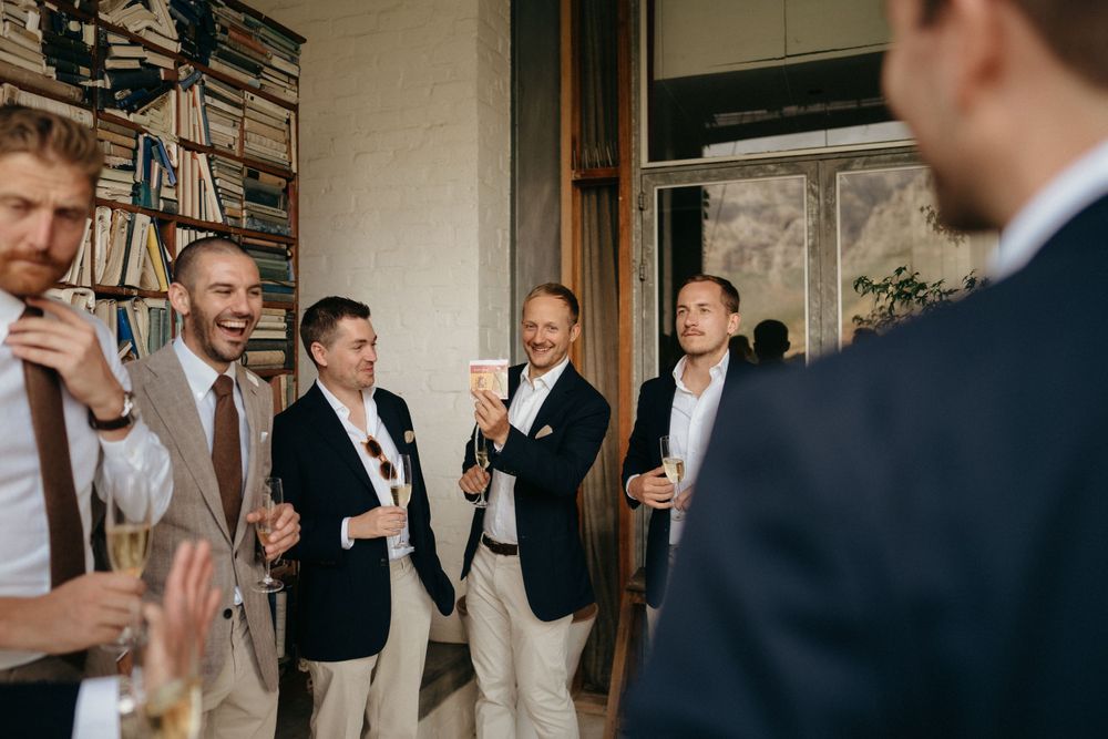 Groomsmen share laughs and cocktails during a wedding celebration.