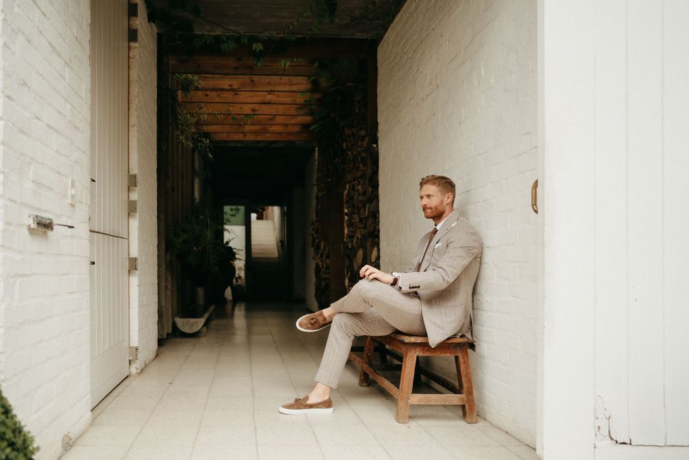 Artistic wedding photo in white corridor with exposed brick and wooden bench.