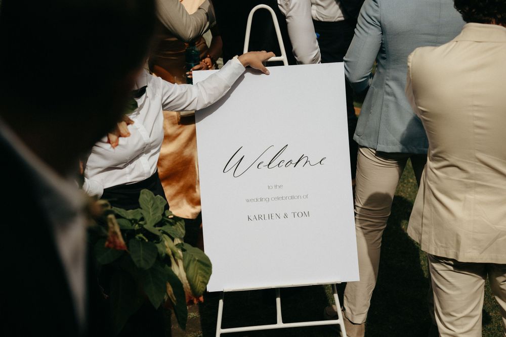 Welcome sign for wedding displayed on white easel stand with elegant calligraphy.