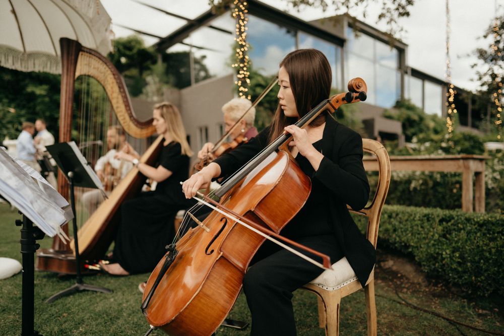 String musicians perform classical music in an outdoor garden setting.