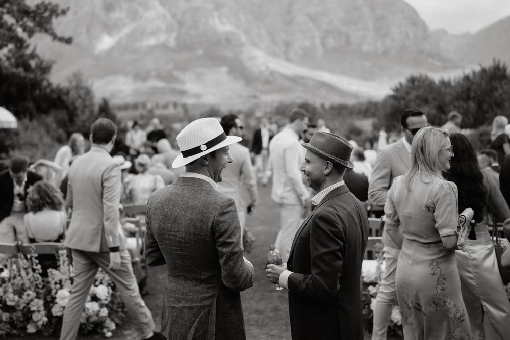 Vintage black and white photo of well-dressed guests mingling at an outdoor mountain gathering.