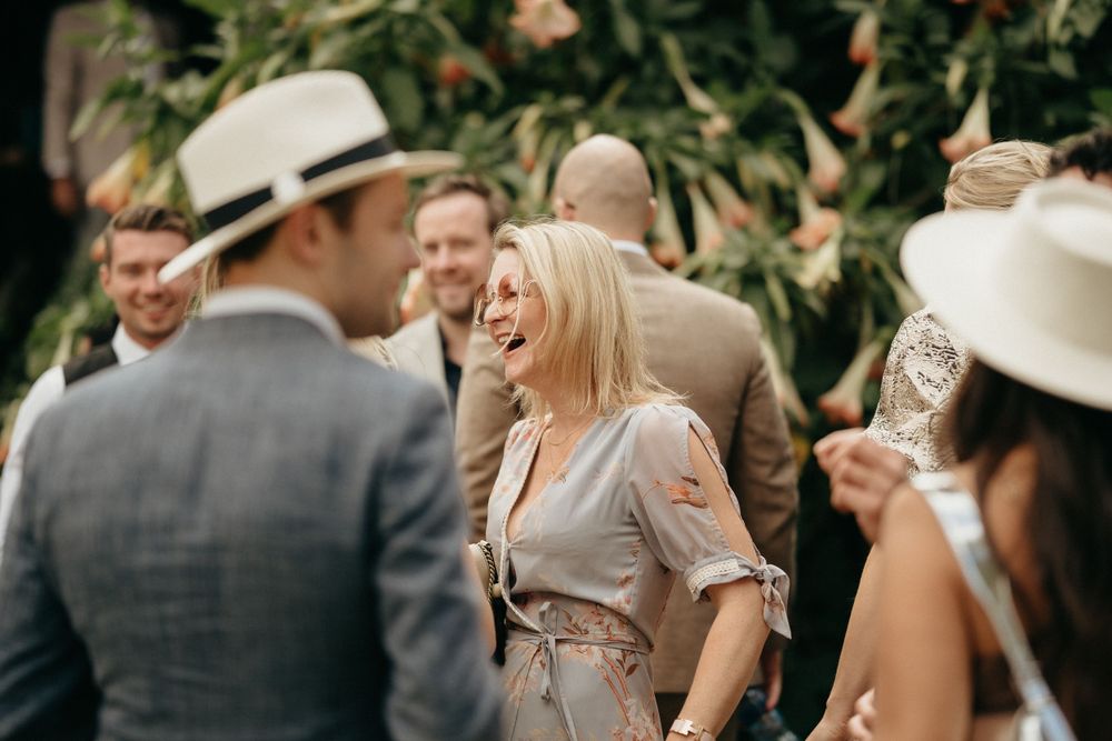 Outdoor garden party scene with guests mingling and laughing while wearing summer attire.