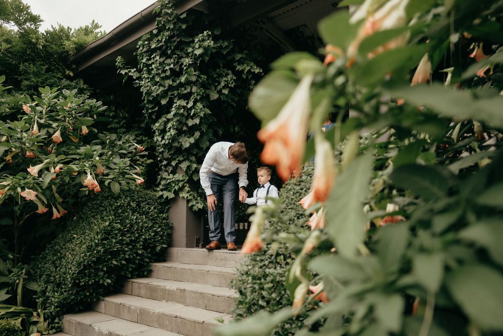 A couple stands on outdoor steps surrounded by lush green foliage and plants.