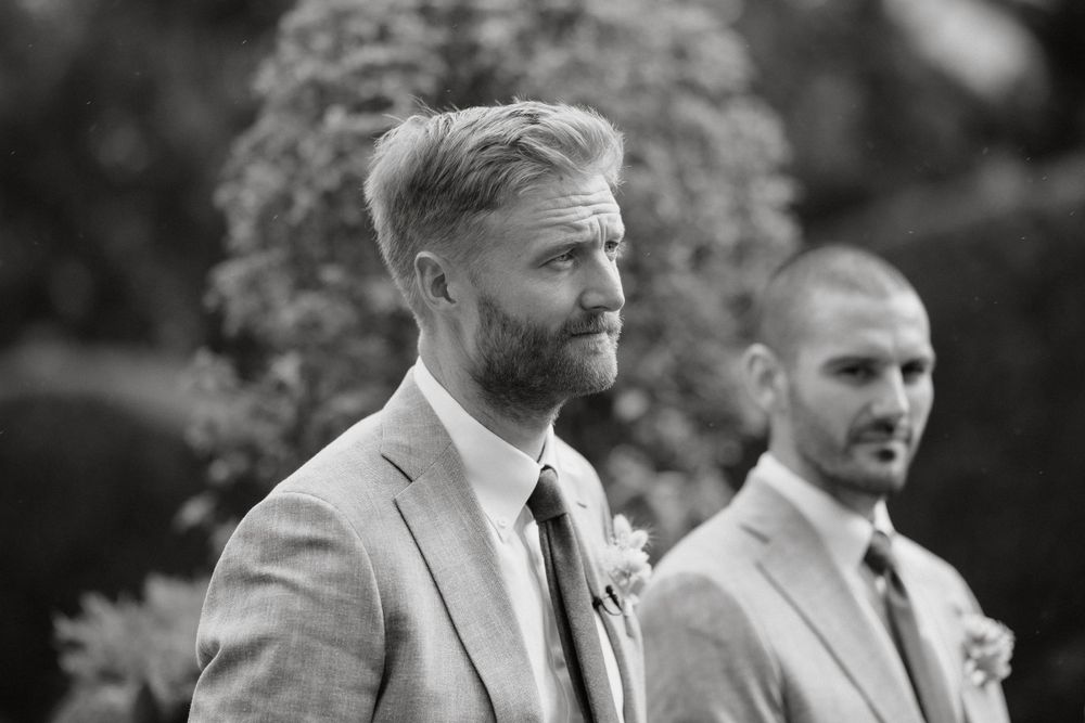 A black and white portrait of groomsmen at an outdoor wedding ceremony.