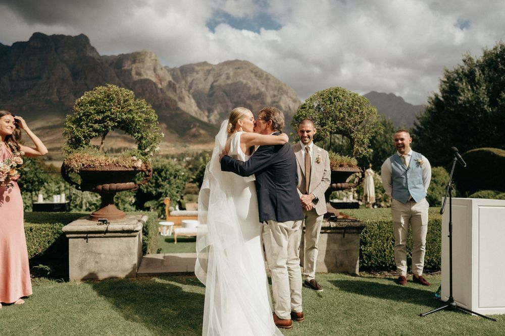 Wedding celebration on a lawn with dramatic mountain scenery in the background.