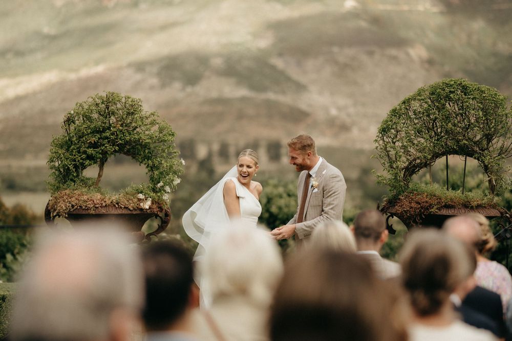 Outdoor wedding ceremony with scenic mountain backdrop and floral arch decorations.