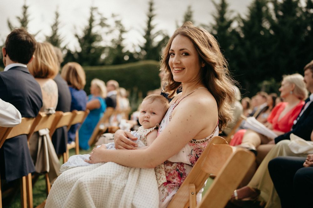 Wedding guests seated in wooden chairs at outdoor ceremony venue.