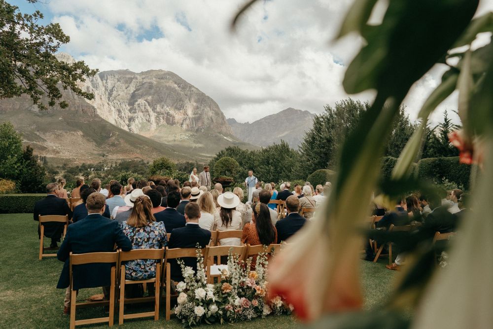 Outdoor wedding ceremony with mountain views and wooden chairs set up on manicured lawn.