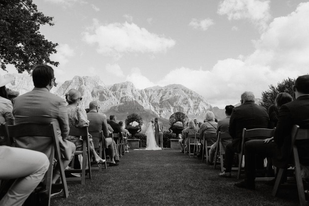 Outdoor wedding ceremony setup with mountain backdrop in black and white photography.