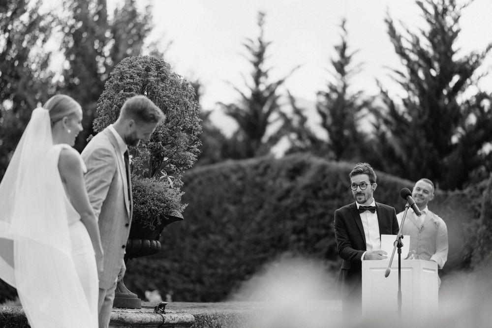 A black and white photograph of a wedding ceremony taking place in a garden setting.