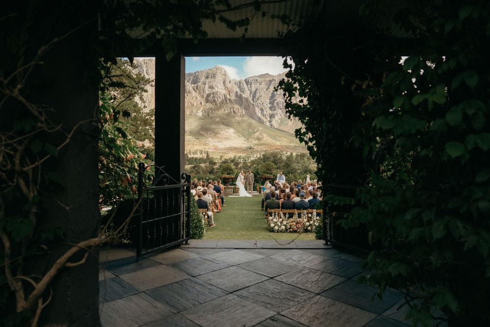 Stone archway frames a wedding ceremony with majestic mountain views beyond.