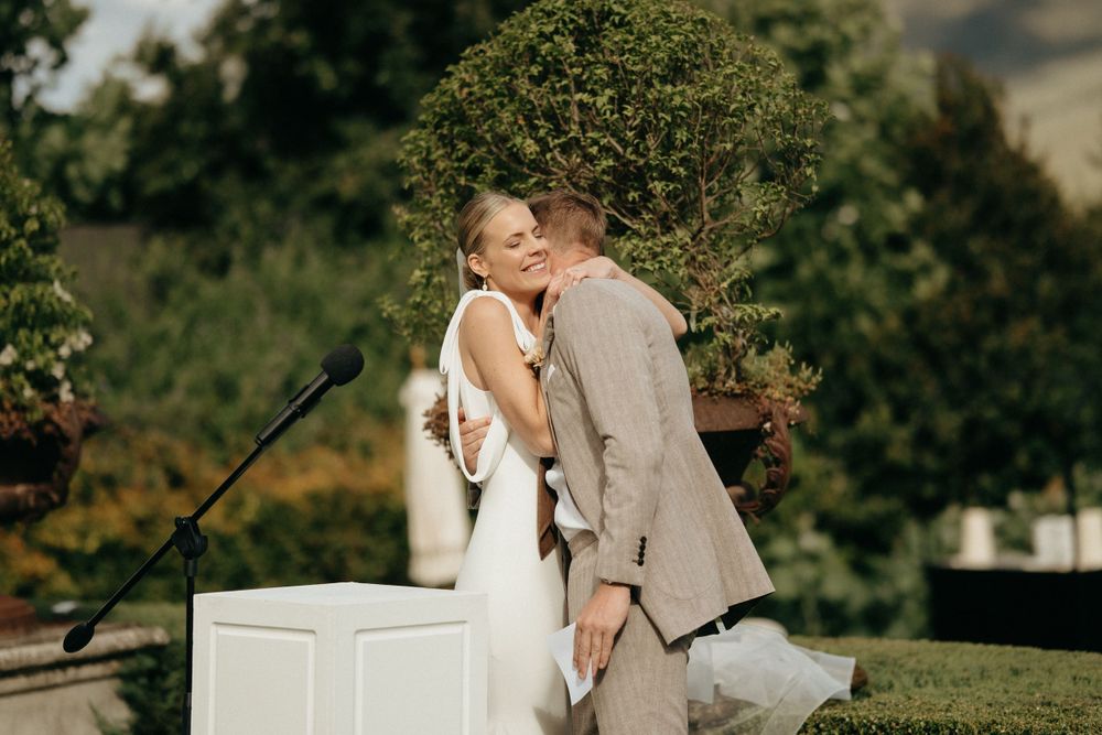 Couple sharing intimate moment during outdoor wedding ceremony against mountain backdrop.
