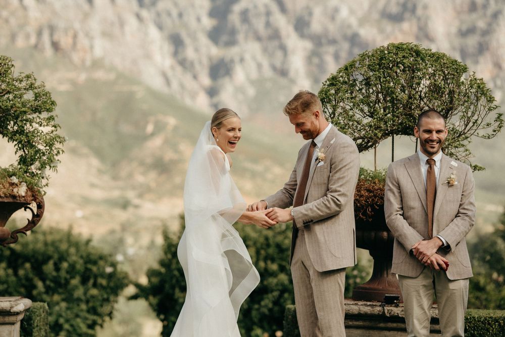 Wedding ceremony moment under decorative trees with majestic mountain landscape.