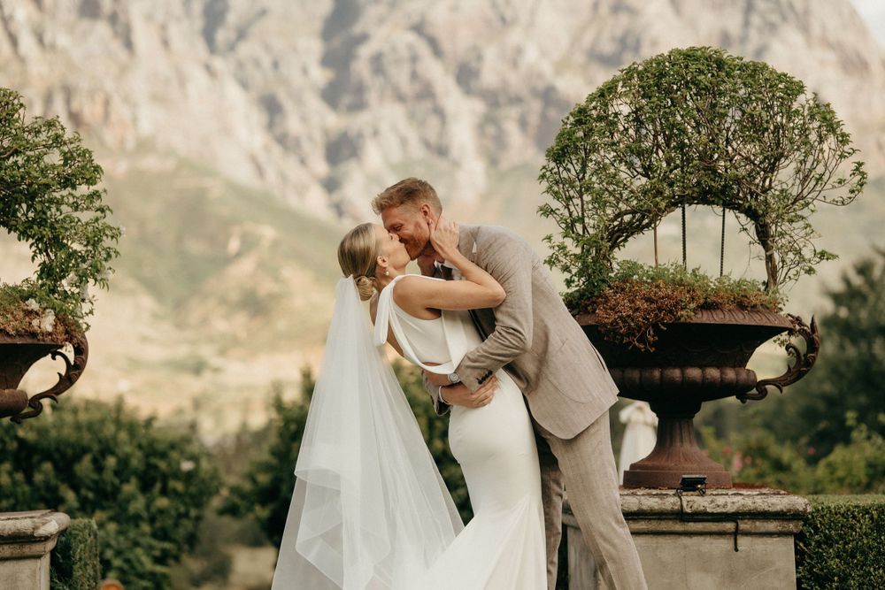 Romantic wedding moment against dramatic mountain landscape with decorative garden planters.