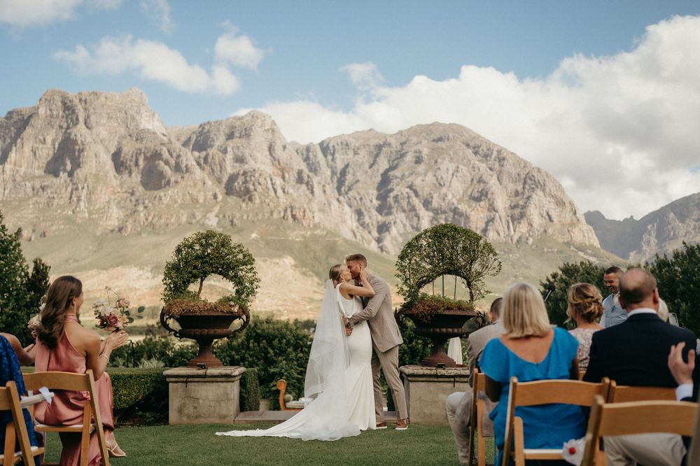 Wedding ceremony with mountain vista and decorative potted plants at outdoor venue.
