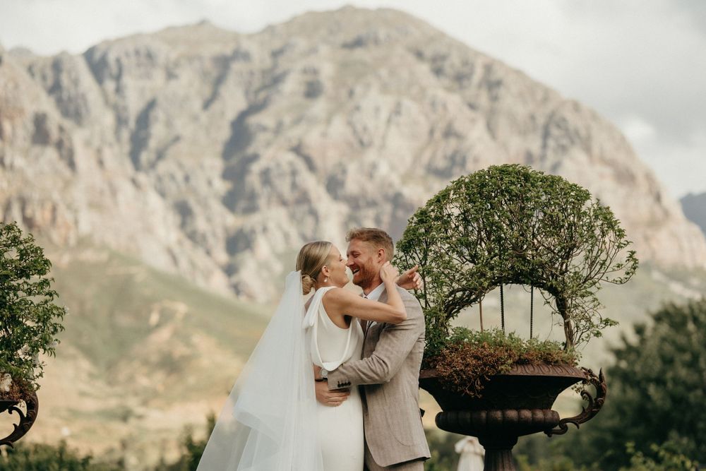 Intimate wedding scene with majestic mountain backdrop and ornamental garden decor.