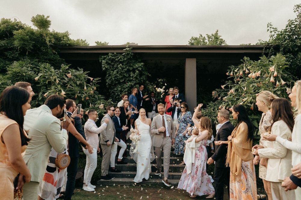 Wedding guests gather on outdoor steps for a celebratory group photo.