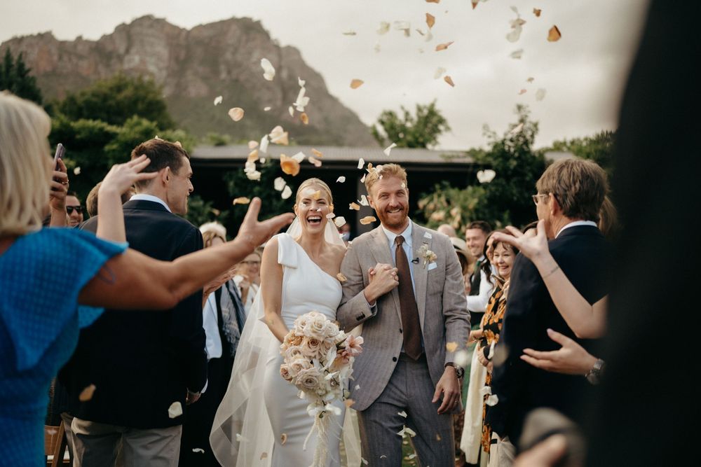 Wedding exit celebration with flower petals being tossed against mountain backdrop.