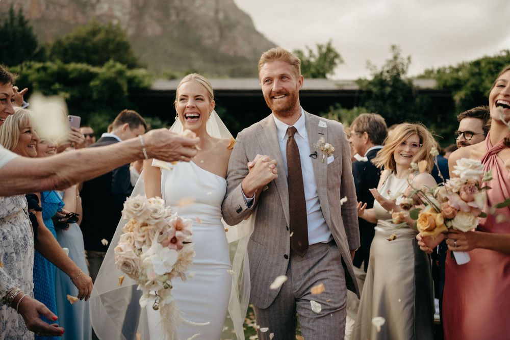 Wedding celebration with guests throwing confetti against a backdrop of mountain scenery.
