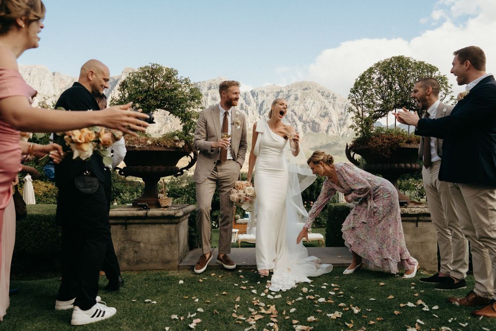 Wedding celebration moment on a lush lawn with confetti and mountain backdrop.